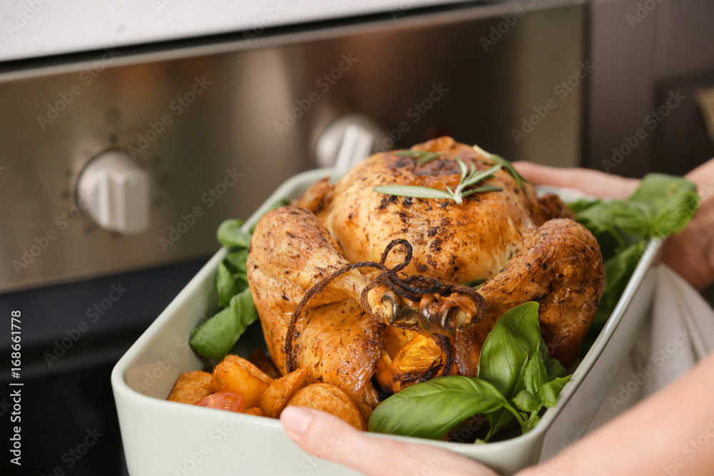 Woman holding baking dish with golden roasted turkey