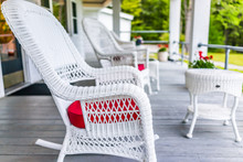 Front Porch Of House With White Rocking Chairs On Wooden Deck