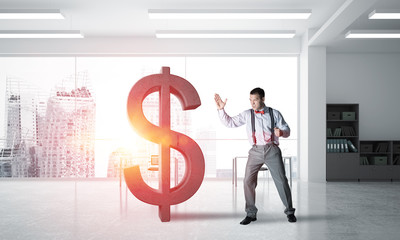 Determined banker man in modern office interior breaking dollar figure