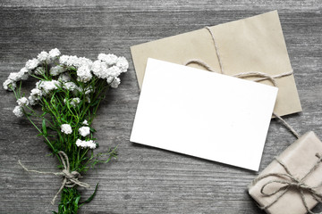 blank white greeting card with white flowers bouquet and envelope with gift box