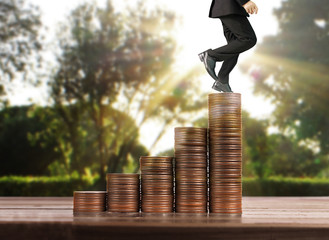 Businessman walk on stack of coins which grows success