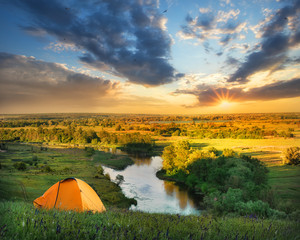 Wall Mural - river under a hill with an orange tent at sunset