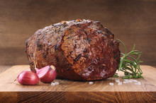 Baked Meat, Garlic And Rosemary On A Wooden Background. Roast Beef.