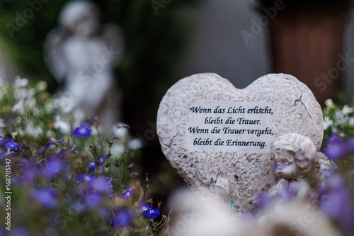 Fotografía Herz aus Stein auf einem Friedhof mit dem Text "Wenn das Licht erlischt, bleibt die Trauer