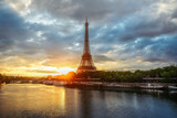 Fototapeta Boho - Scenic view over the Eiffel Tower from a bridge at sunrise. Paris, France. Beautiful travel background with rising sun and dramatic clouds.