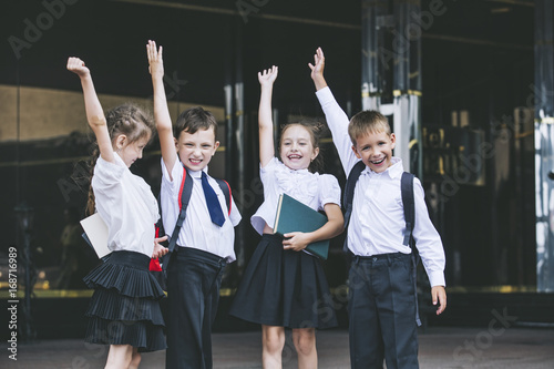Zdjęcie XXL Piękne dzieci w wieku szkolnym aktywne i szczęśliwe na tle szkoły w mundurze