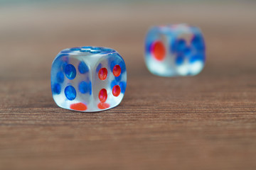 Wall Mural - Two transparent dices on wooden board. Six sides with blue and red points. Artistic blurring.