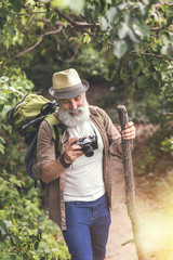 Wall Mural - Happy mature male tourist photographing wild nature