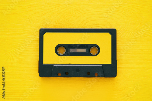 Fotografía Retro cassette tape over yellow wooden table. top view.
