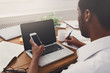 © Prostock-studio - African-american businessman in office with mobile and laptop