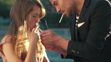 Man And A Woman Smoking Cigarettes Together. Cigarette Lighter In Hands Man.