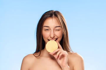 Wall Mural - Beautiful young woman on a blue background holds a make-up sponge