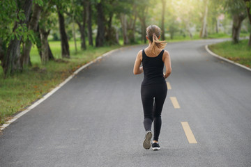 Wall Mural - Young fitness sport woman running on the road in the morning, Sun light flare , Selective focus.