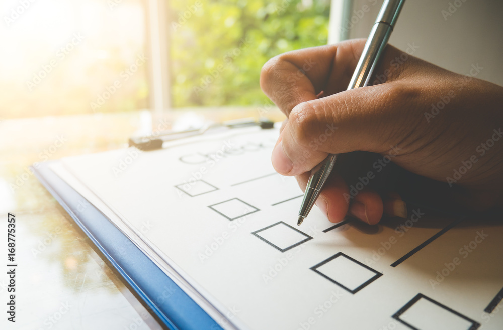 человек заполняет чек-лист с ручкой и бумагой