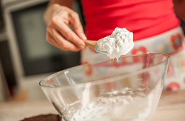 Adult woman whipping cream with whisk in glass bowl