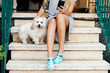 © sosann/Stocksy - Legs of woman sitting on a staircase, with her dog