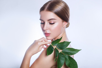 organic cosmetic . Beautiful woman face portrait with green leaf , concept for skin care or organic cosmetics