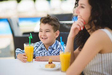 Boy and mother or happy family having healthy breakfast in resort cafe outdoor