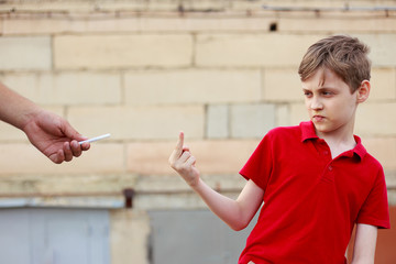 Boy showing middle finger refusing the proposed cigarette. Bad habits, healthcare, stop smoking concept