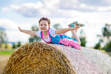 Wall Mural - Cute little kid girl in traditional Bavarian costume in wheat field