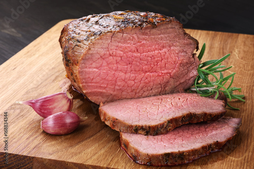 Fotografie, Obraz Baked meat, garlic and rosemary on a wooden background