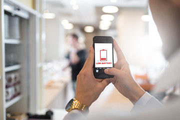 Businessman holding mobile phone with low battery symbol and battery