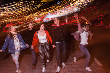 Young people party in city. Free nightlife. Happy students outdoors, strong friendship, bright lights background