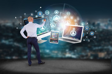 Poster - businessman in front of a wall with computer and devices displayed on a futuristic interface with bu