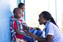 Nurse Examing Mother And Daughter In Clinic. Kenya, Africa.