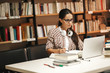 © BalanceFormCreative - Young female student study in the school  library.She using laptop and learning online.