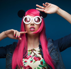 fashion girl with pink hair and big sunglasses over blue  background