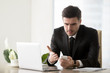 © fizkes - Angry businessman annoyed with phone call while working on laptop at office, receiving bad news on smartphone, irritated by spamming message, mobile not working, battery needs recharge, broken cell