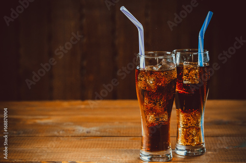 Fotografia Beautiful cold drink of Cola with ice cubes with a boiler straws in glasses on w