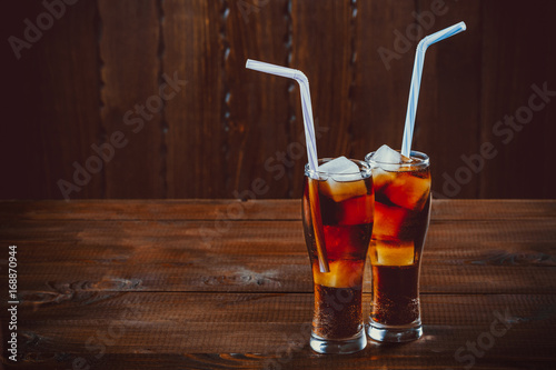 Fotografia Beautiful cold drink of Cola with ice cubes with a boiler straws in glasses on w