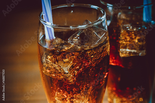 Fotografia Beautiful cold drink of Cola with ice cubes with a boiler straws in glasses on wooden background with free space