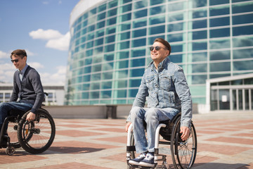 Wall Mural - Shot of a young man spending time in a park with his friend using a wheelchair