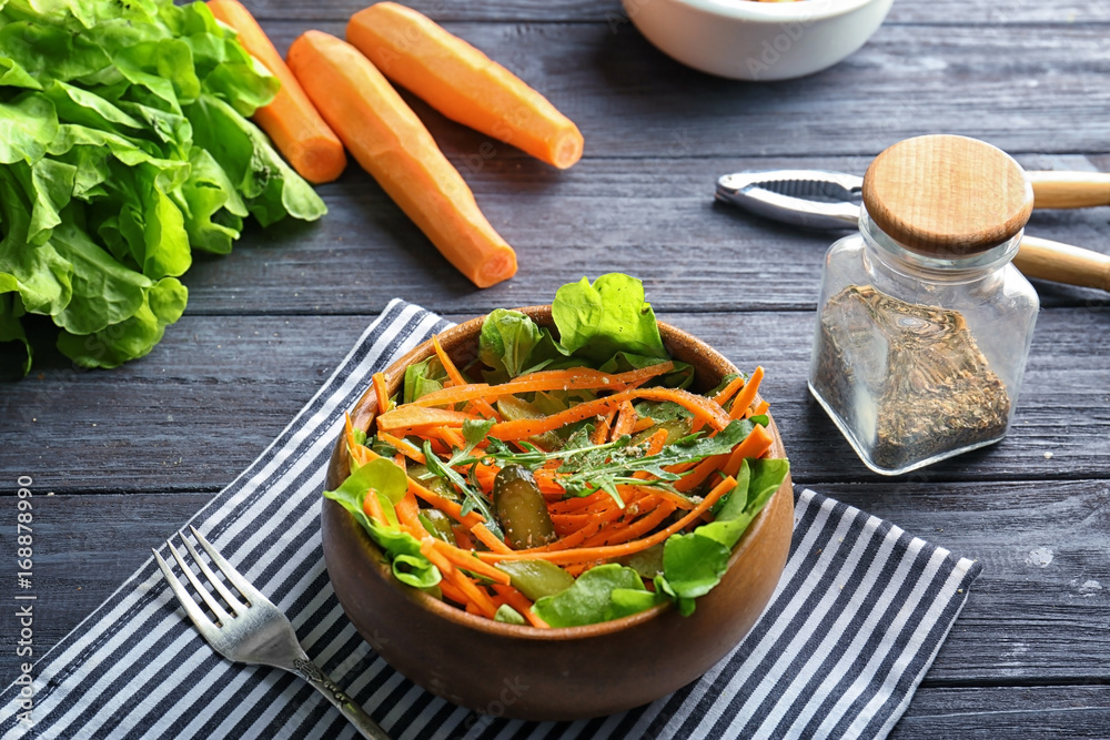 Bowl with delicious carrot salad on table