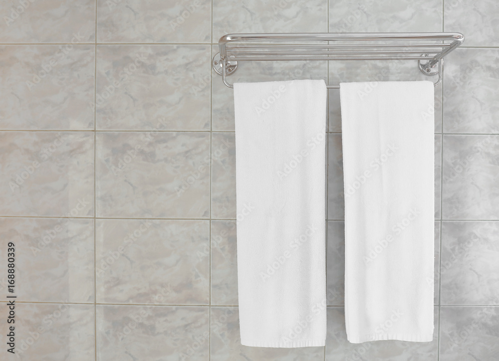 Rack with towels on wall in hotel bathroom