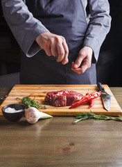 Wall Mural - Chef seasoning rib eye steak on wooden board at restaurant kitchen