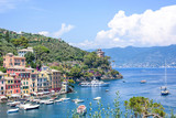 Fototapeta  - Beautiful aerial daylight view from top to ships on water and buildings in Portofino city of Italy. Tourists walking on sidewalk. Top view