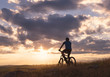 © RGBImages/Stocksy - Man on bicycle standing on top of hill at sunset