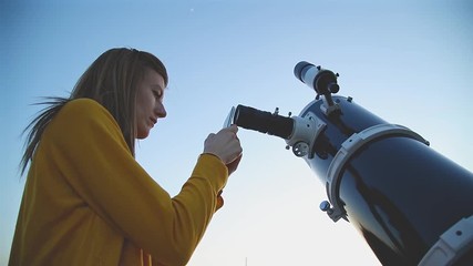 Wall Mural - girl using cellphone and photographing through a telescope.