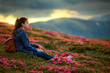 © Serhii - Flowers in the mountains. Shot of a young woman looking at the landscape while hiking in the mountains. Magic pink rhododendron flowers on summer mountain