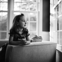 Black And White Portrait Of A Young Girl Looking Out A Window
