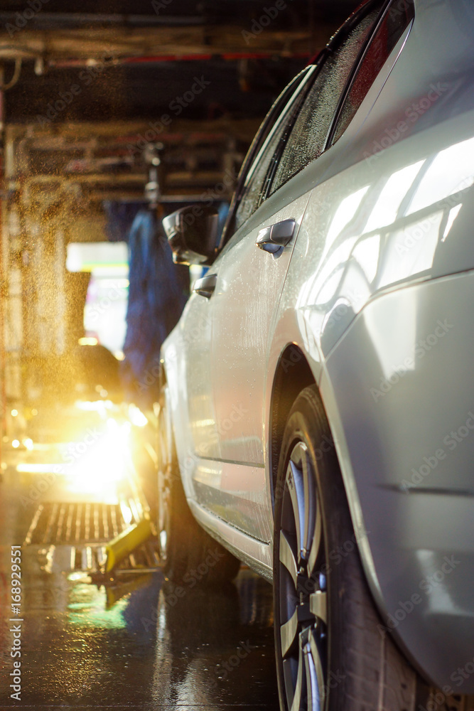 Car wash, black car in automatic car wash, rotating red and blue brush. Washing vehicle.