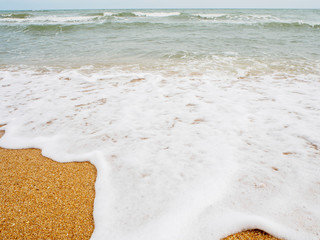 Wall Mural - Wide angle view of a large tide with white sea foam crashing into the shores of a beach. Chantaburi, Thailand. Travel and nature concept.