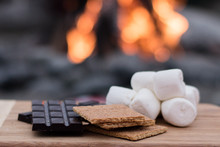 Smores Ingredients At A Beach Bonfire With Chocolate, Marshmellow, And Graham Crackers With Room For Copy