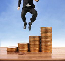 Businessman walk on stack of coins which grows success