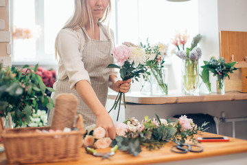 Wall Mural - Florist workplace: woman arranging a bouquet with roses, matthiolas, ranunculus flowers and gypsophila paniculata twigs.