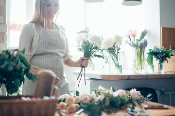 Wall Mural - Cute concentrated young female florist in glasses working in flower shop